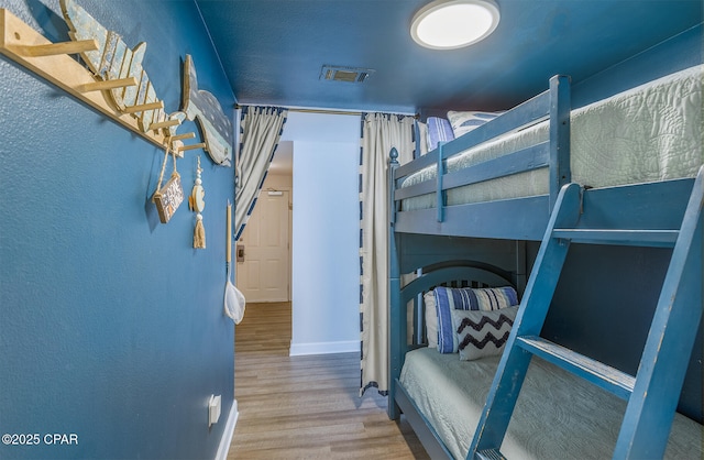 bedroom with visible vents and wood finished floors