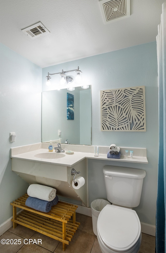 half bath with tile patterned flooring, visible vents, toilet, and a sink