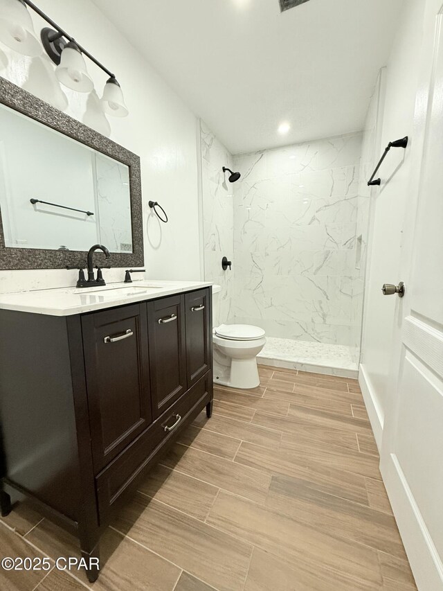 816 N E, Panama City, FL 32401 - bathroom featuring wood finish floors, tiled shower, toilet, and vanity