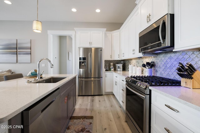 227 Sands St, Panama City Beach, FL 32413 - kitchen featuring appliances with stainless steel finishes, white cabinets, light wood-style floors, decorative backsplash, and recessed lighting