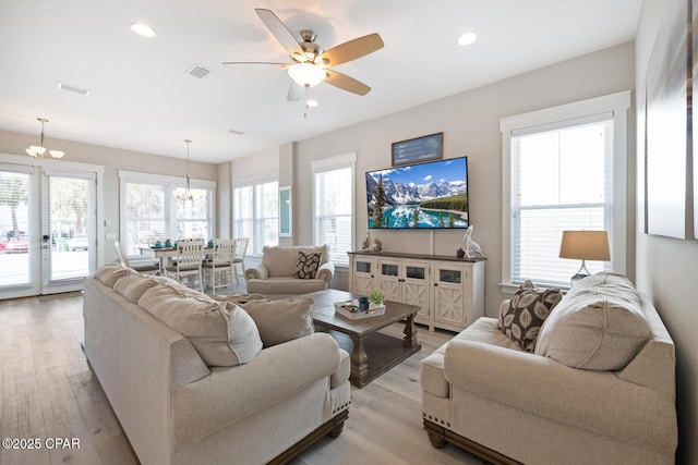 living area featuring visible vents, recessed lighting, ceiling fan with notable chandelier, and light wood-style floors