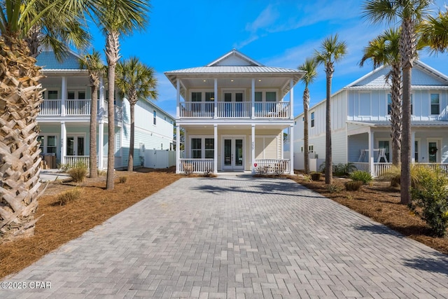 view of front of home with french doors, decorative driveway, a balcony, and covered porch