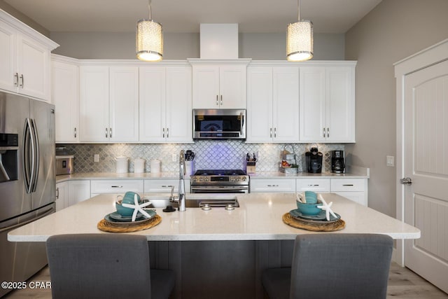 kitchen featuring a kitchen breakfast bar, backsplash, appliances with stainless steel finishes, and white cabinets