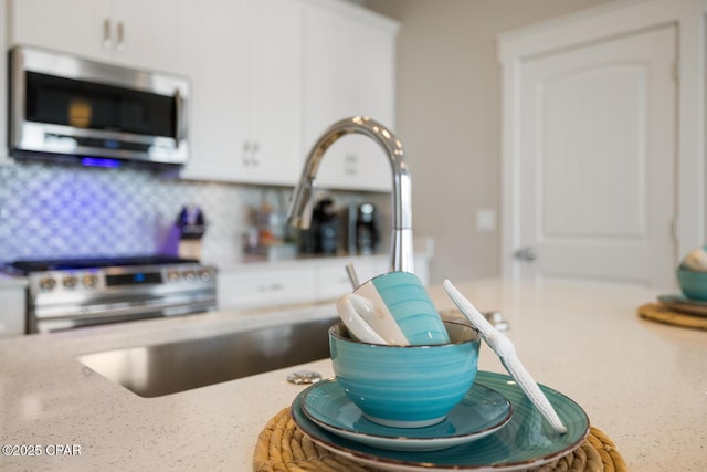 details with light stone countertops, appliances with stainless steel finishes, and white cabinetry