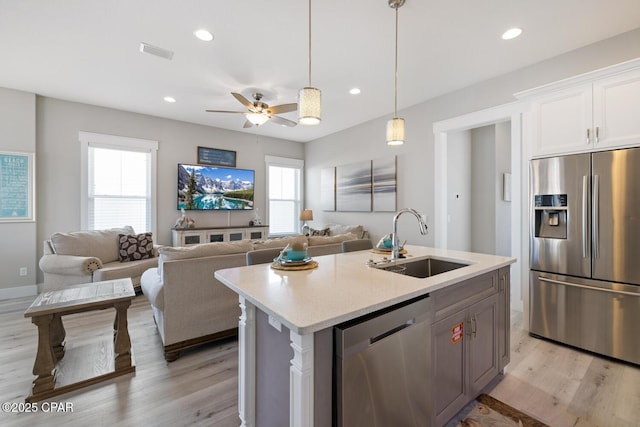 kitchen featuring visible vents, light wood-style flooring, a sink, stainless steel appliances, and light countertops