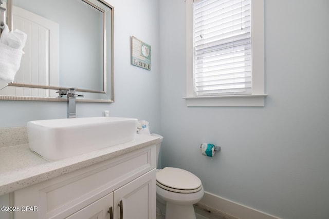 bathroom with vanity, toilet, and baseboards