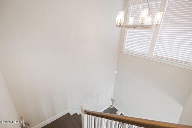 staircase featuring a notable chandelier, baseboards, and wood finished floors