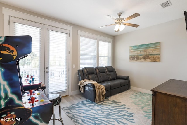 living area featuring light wood-style floors, baseboards, visible vents, and ceiling fan