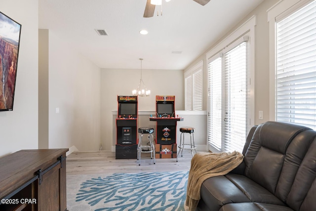 office area with recessed lighting, visible vents, light wood-style flooring, and ceiling fan with notable chandelier