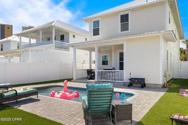 back of property featuring a standing seam roof, fence, metal roof, a fenced in pool, and a patio area