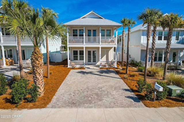 view of front of property with french doors, driveway, covered porch, and metal roof