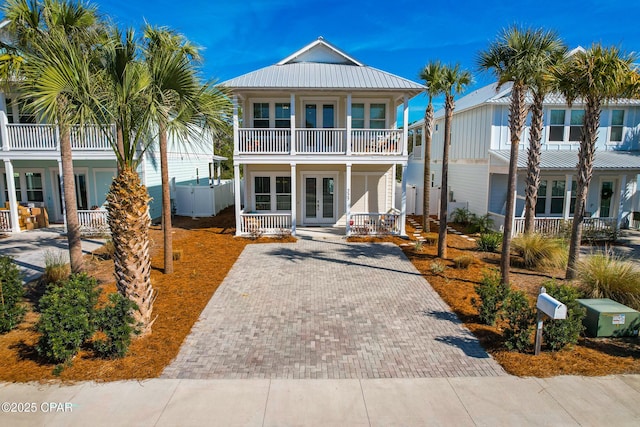 227 Sands St, Panama City Beach, FL 32413 - view of front of house with french doors, a porch, driveway, a balcony, and a metal roof