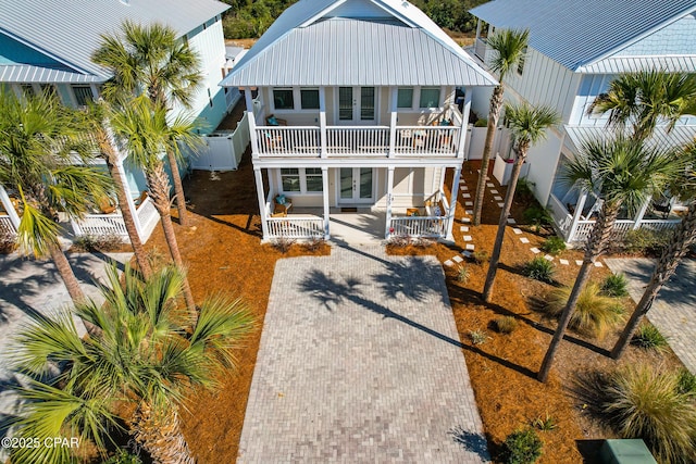 back of property with fence, a porch, french doors, metal roof, and a balcony