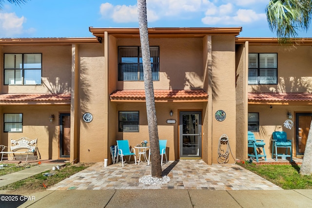 back of property featuring stucco siding, a tile roof, and a patio