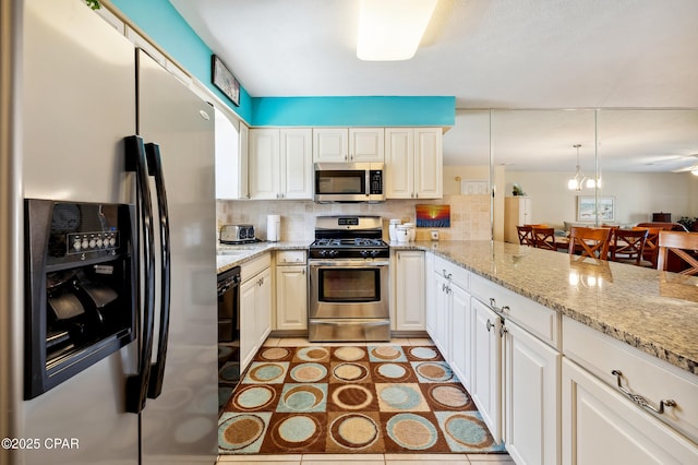 kitchen featuring light tile patterned flooring, backsplash, appliances with stainless steel finishes, and light stone counters