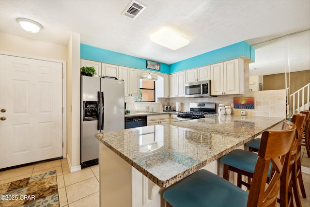 kitchen featuring a peninsula, visible vents, backsplash, and stainless steel appliances