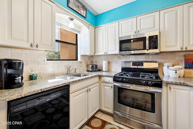 kitchen with decorative backsplash, light stone countertops, appliances with stainless steel finishes, and a sink