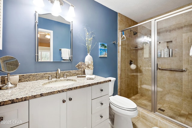 bathroom with tile patterned floors, a stall shower, toilet, and vanity