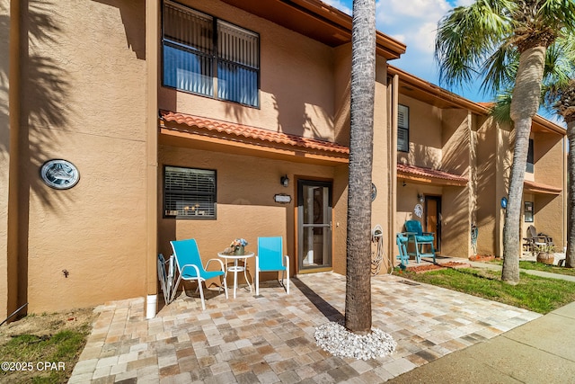 back of property featuring stucco siding, a patio, and a tile roof