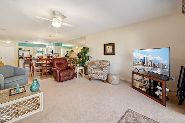 living area with light colored carpet, baseboards, and a ceiling fan