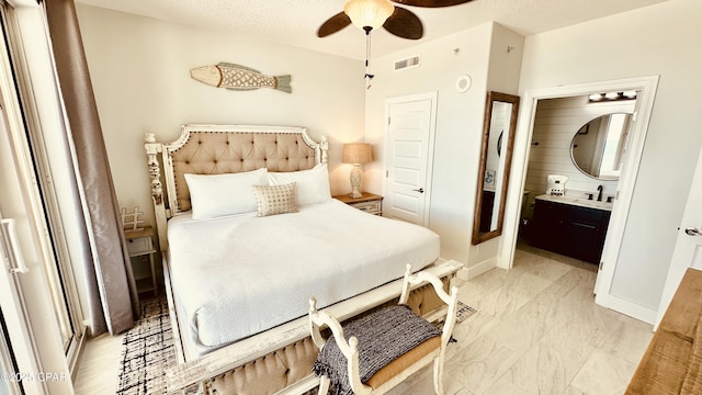 bedroom featuring baseboards, ceiling fan, ensuite bathroom, marble finish floor, and a textured ceiling