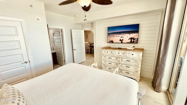 bedroom featuring wooden walls, ceiling fan, a textured ceiling, and light wood-style floors