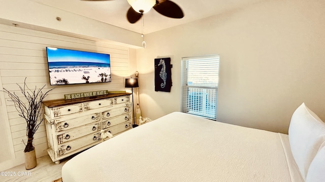 bedroom featuring wooden walls and ceiling fan