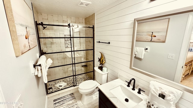 full bath with vanity, visible vents, a stall shower, a textured ceiling, and toilet