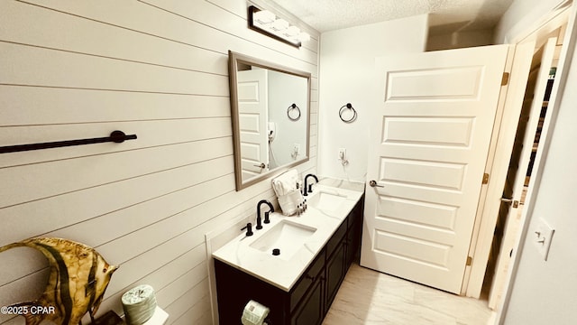 bathroom featuring double vanity, marble finish floor, a textured ceiling, and a sink