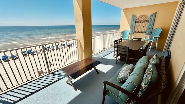 balcony featuring an outdoor living space, a beach view, and a water view