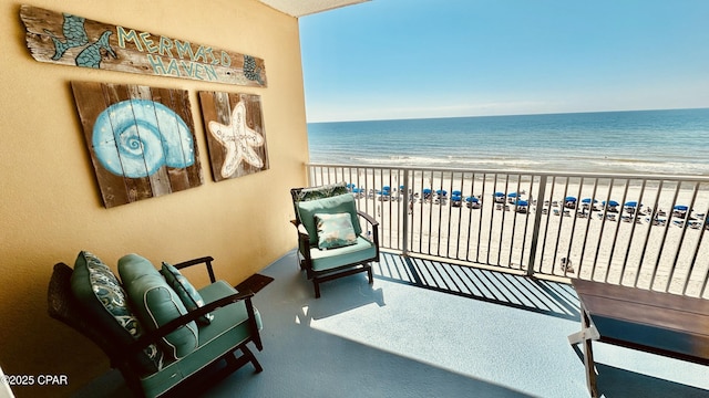 balcony featuring a view of the beach and a water view