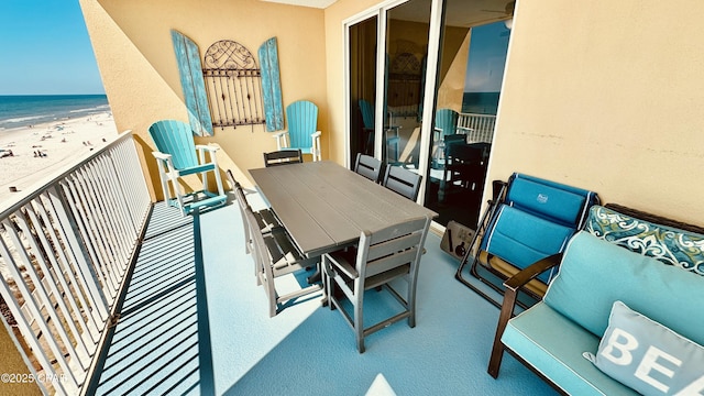 balcony with outdoor dining space, a view of the beach, and a water view