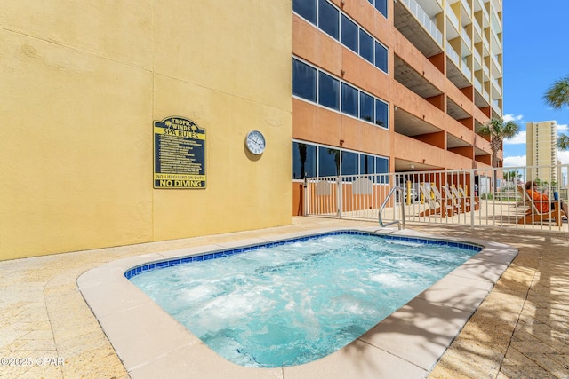 view of pool with a community hot tub and fence