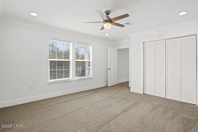 unfurnished bedroom featuring a closet, carpet flooring, baseboards, visible vents, and ornamental molding