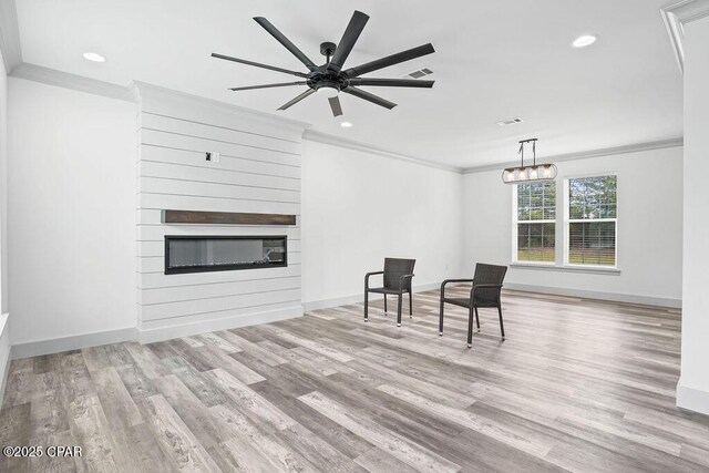 sitting room featuring a large fireplace, recessed lighting, crown molding, and wood finished floors