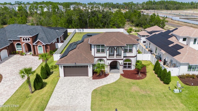 view of front facade featuring a front lawn, fence, a residential view, decorative driveway, and a garage