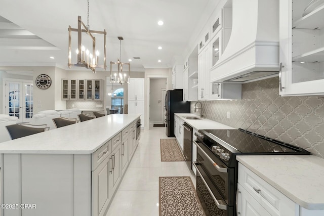 kitchen with black appliances, a sink, a spacious island, custom exhaust hood, and a chandelier