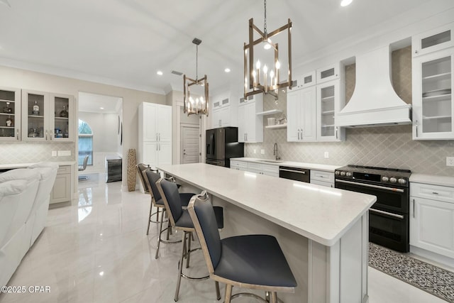 kitchen featuring a notable chandelier, custom range hood, black fridge with ice dispenser, stainless steel dishwasher, and range with two ovens