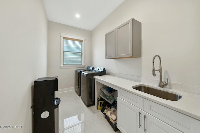 laundry area with a sink, baseboards, cabinet space, and washing machine and dryer