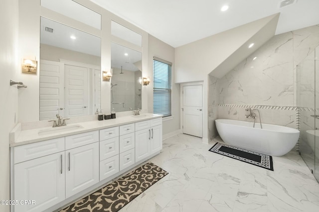 bathroom with a sink, a freestanding bath, marble finish floor, and double vanity