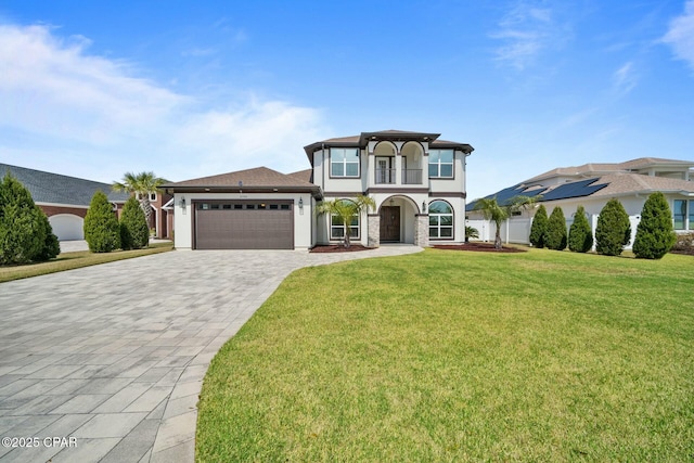 view of front of property with a front yard, stucco siding, decorative driveway, a balcony, and an attached garage