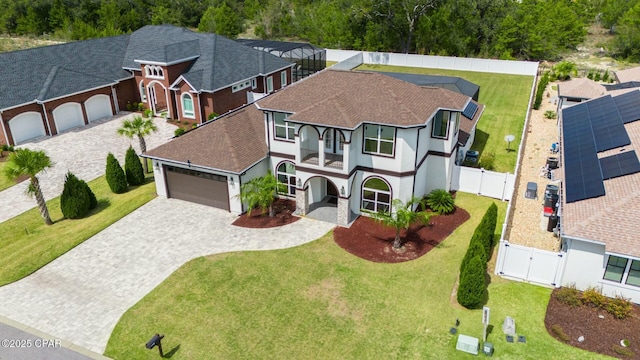 view of front facade with a front lawn, decorative driveway, a fenced backyard, an attached garage, and a gate