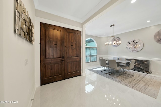 foyer with recessed lighting, wainscoting, a chandelier, and crown molding