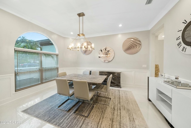 dining room with a chandelier, a decorative wall, wainscoting, and ornamental molding