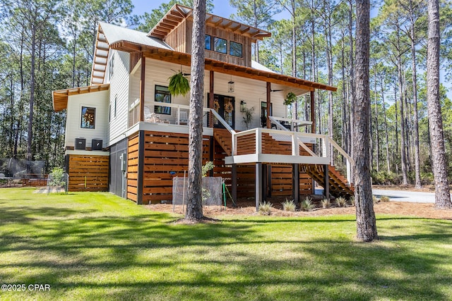 rear view of property featuring stairway, board and batten siding, a lawn, and a porch