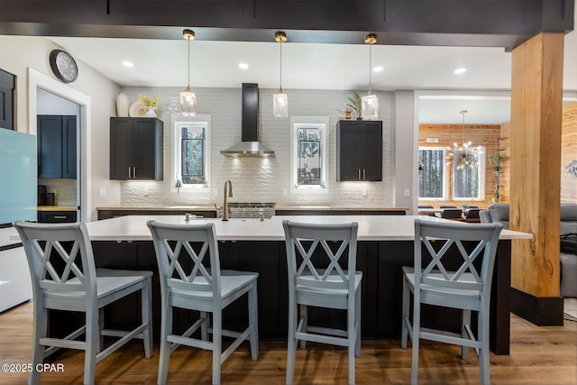 kitchen with decorative backsplash, light countertops, and wall chimney exhaust hood