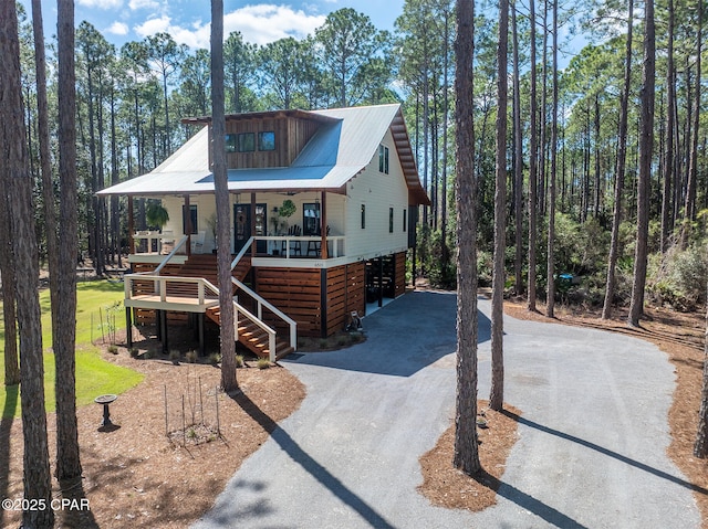 chalet / cabin featuring aphalt driveway, stairway, covered porch, and metal roof