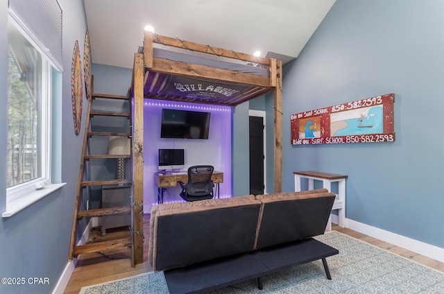 living room featuring baseboards, wood finished floors, and vaulted ceiling