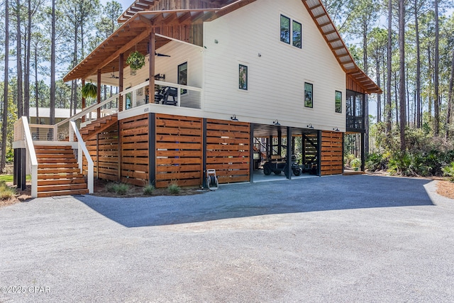 view of side of property featuring a carport, stairway, driveway, and ceiling fan