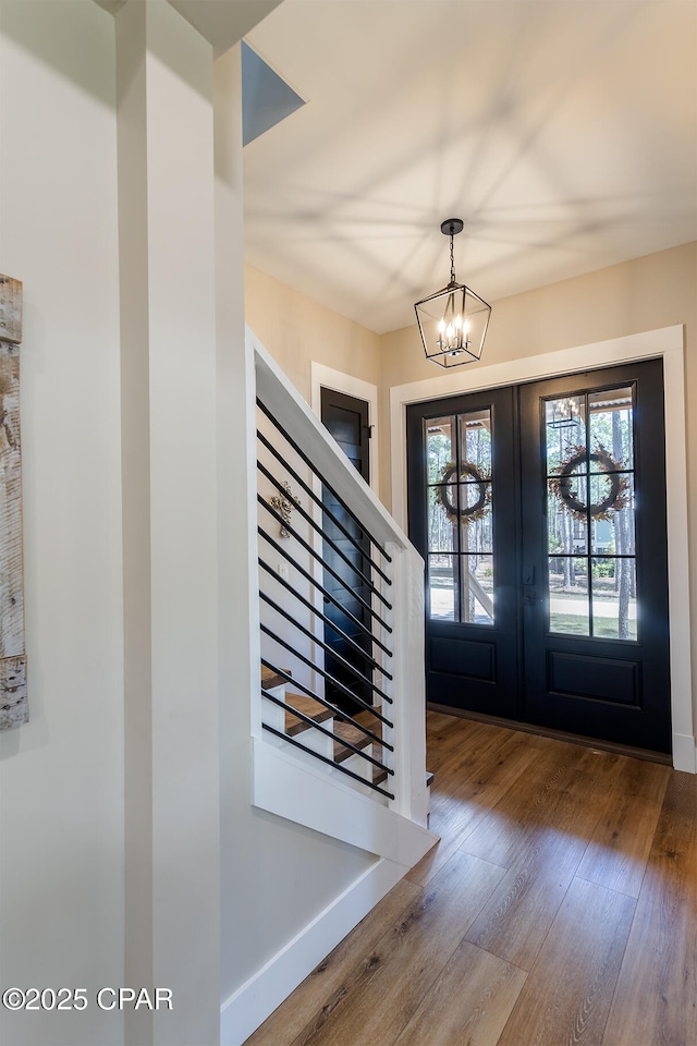 foyer entrance featuring hardwood / wood-style flooring, a notable chandelier, french doors, and baseboards